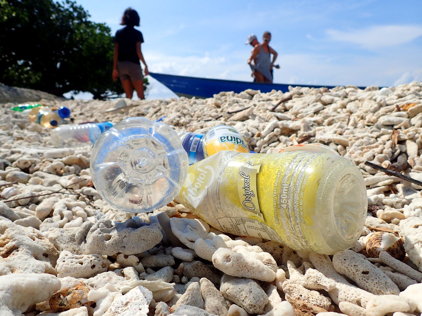 Bottles on the beach with people surveying in the background, Penyusuk